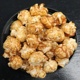 Bourbon Bacon Caramel popcorn in a bowl, coated with sweet caramel and real bourbon, featuring bacon pieces.