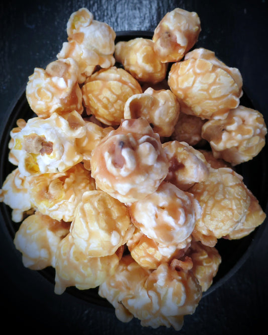 Maple and bacon flavored popcorn in a black bowl.