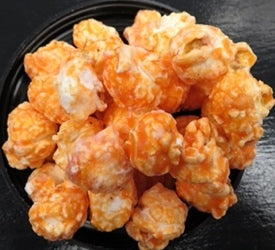 Orange cream flavored popcorn in a black bowl.