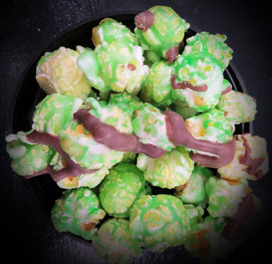 Mint chocolate chip popcorn with chocolate drizzle on a black background.