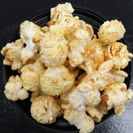 Popcorn with hot dog and ketchup flavors on a black plate.