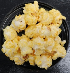 Beer cheese flavored popcorn with a spicy kick on a black plate.