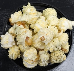 Jalapeno beer-flavored popcorn in a black bowl on a dark surface.