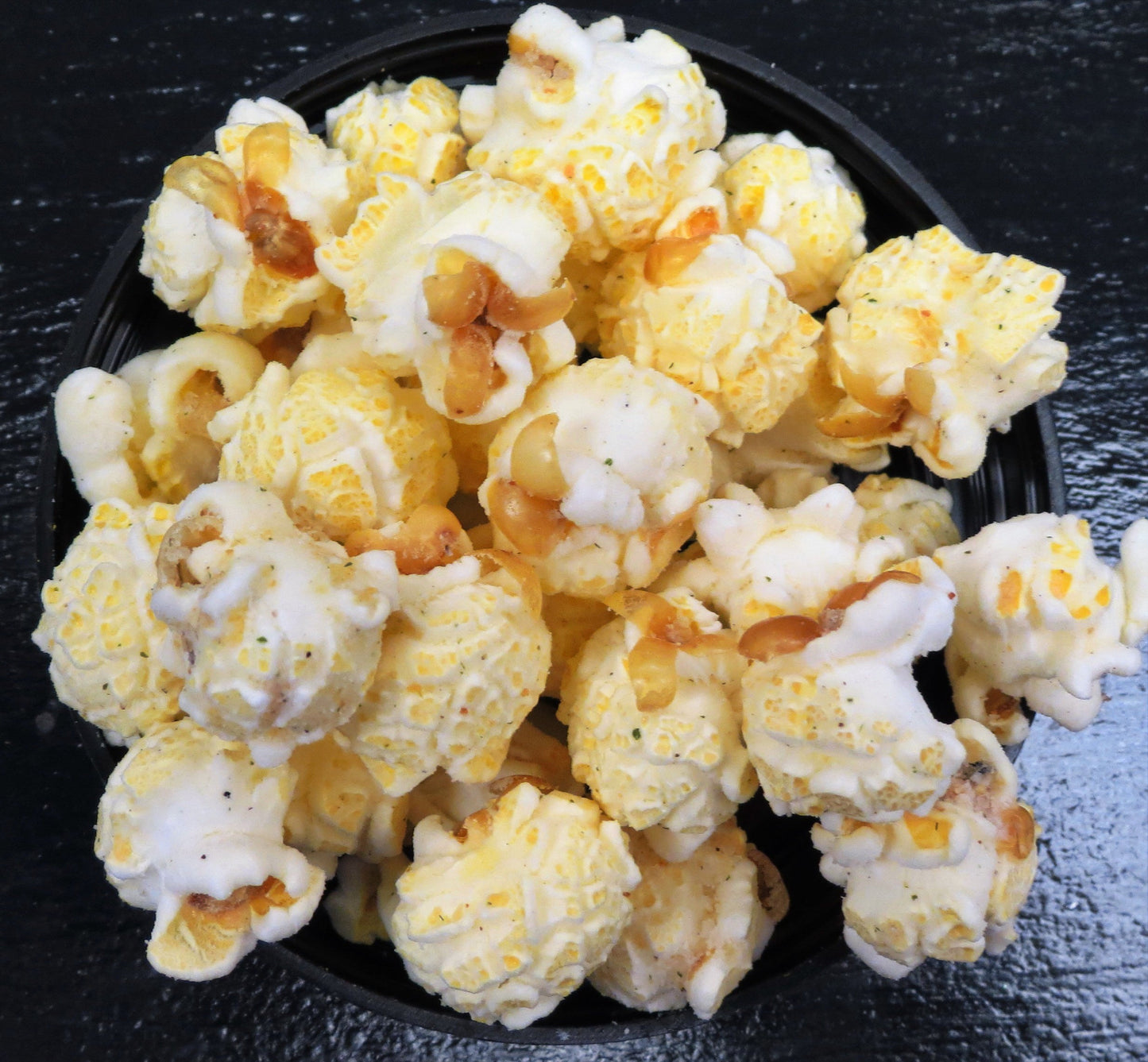 Parmesan Garlic popcorn in a black bowl on a dark surface.