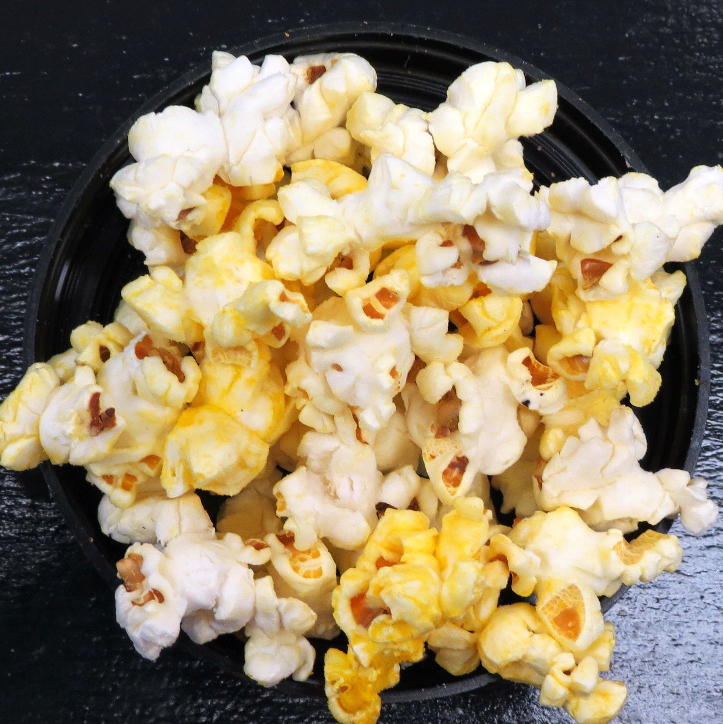 Movie theater style salt and butter popcorn in a black bowl.