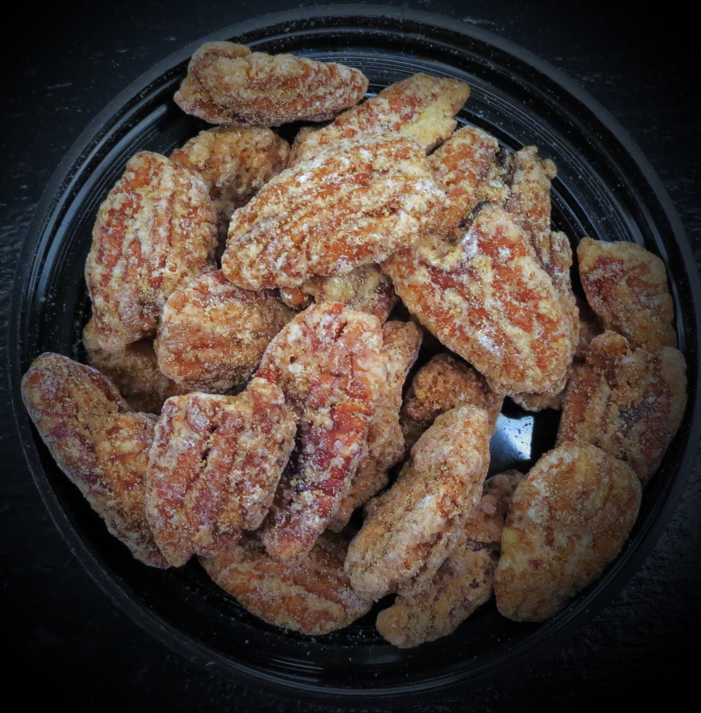 Praline Pecans in a black bowl, coated with brown sugar and vanilla.
