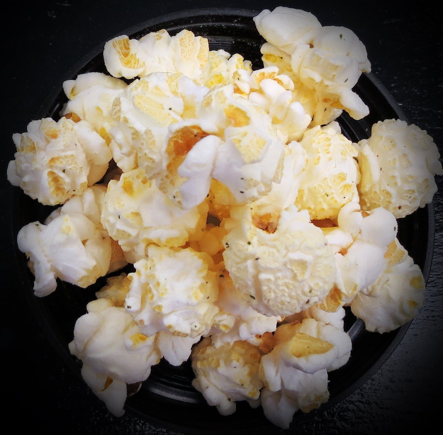 Horseradish & Bacon flavored popcorn in a black bowl.