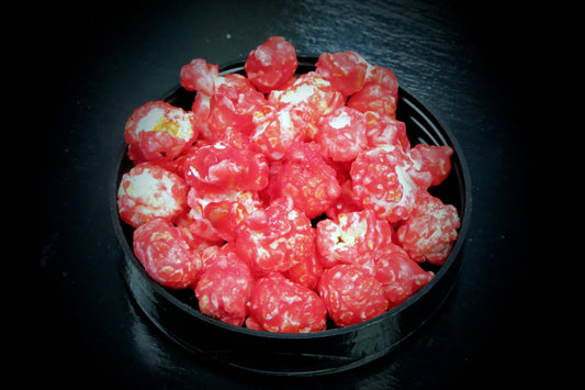 Red cinnamon whiskey-flavored popcorn in a black bowl.
