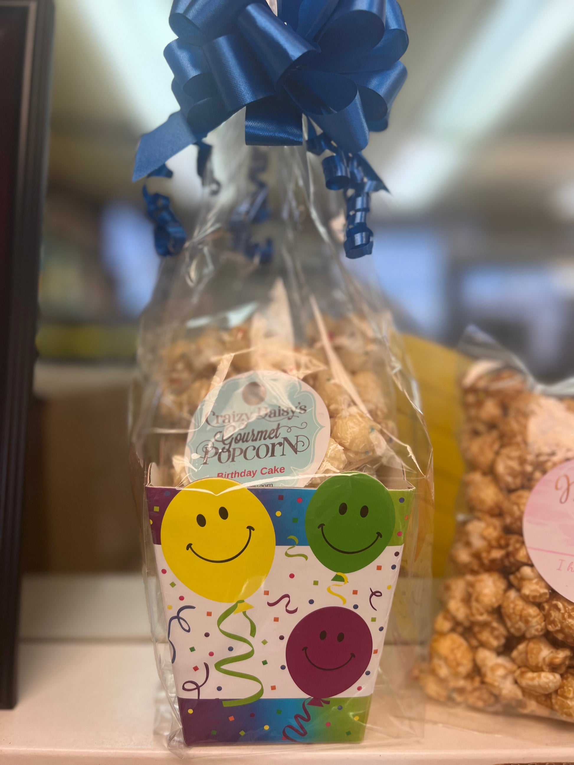 Birthday snack bag with colorful smiley face design and tied with a blue ribbon, perfect for gifting.
