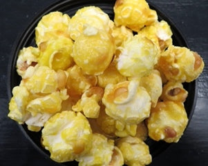 Butterscotch flavored popcorn in a black bowl.