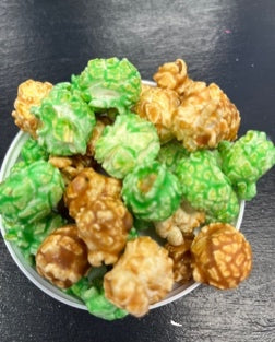 Caramel apple popcorn mix in a bowl, featuring green apple and caramel-coated pieces.